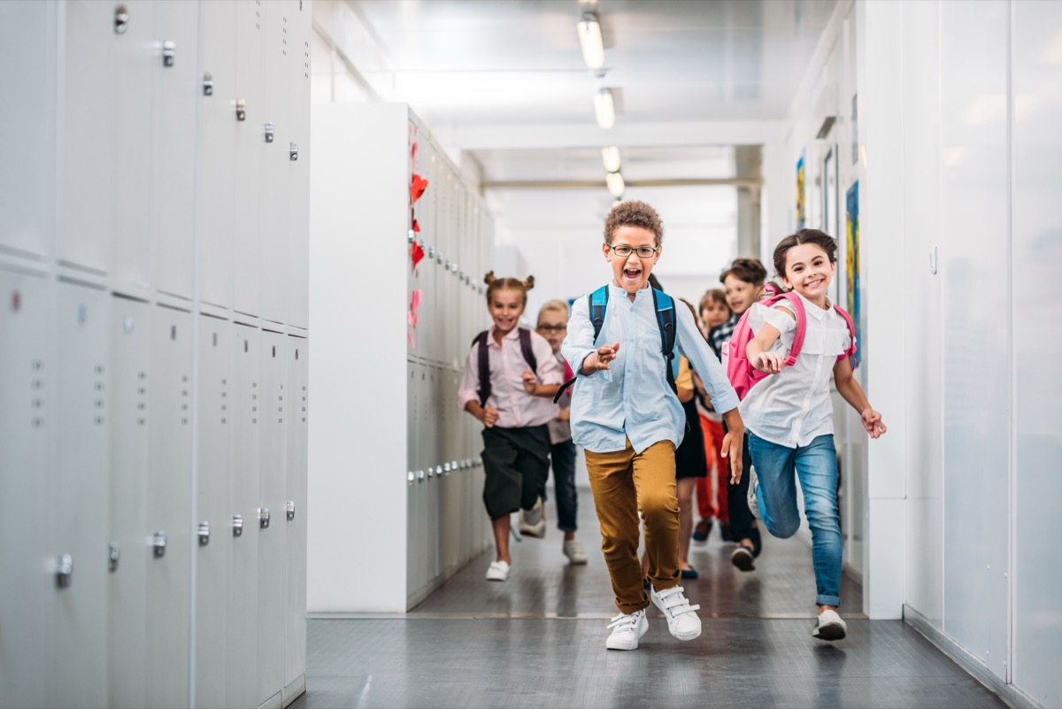 Happy students running through school hallway at dismissal time